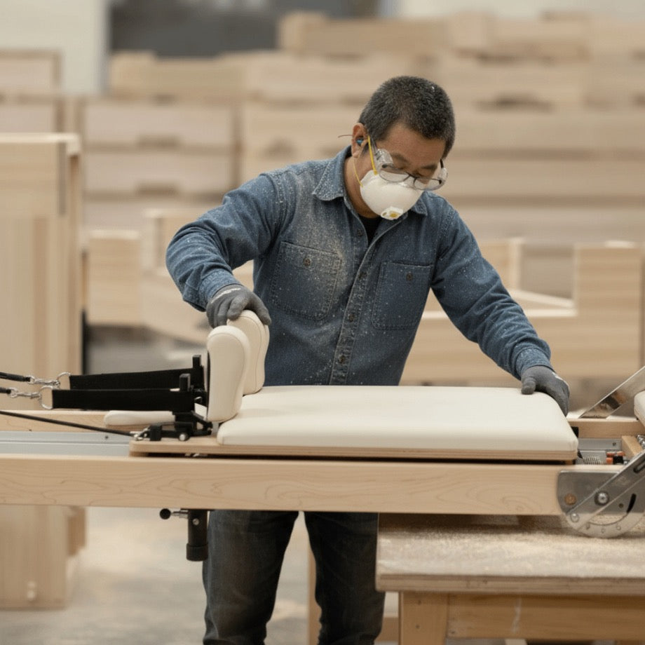 Craftsman hand-assembling a Studio Reformer in the workshop